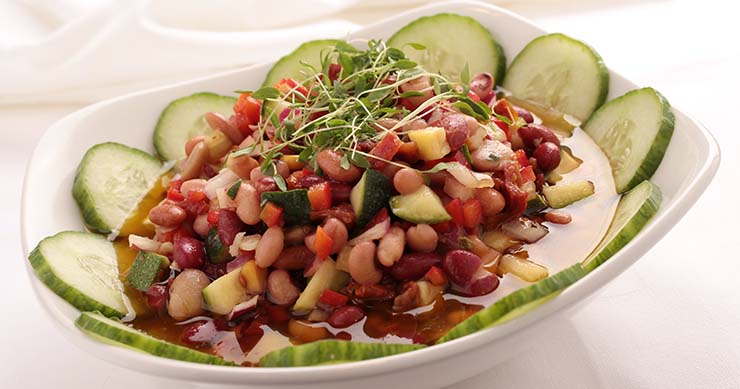 A bean and vegetable salad with cucumber slices around the edge of a bowl.