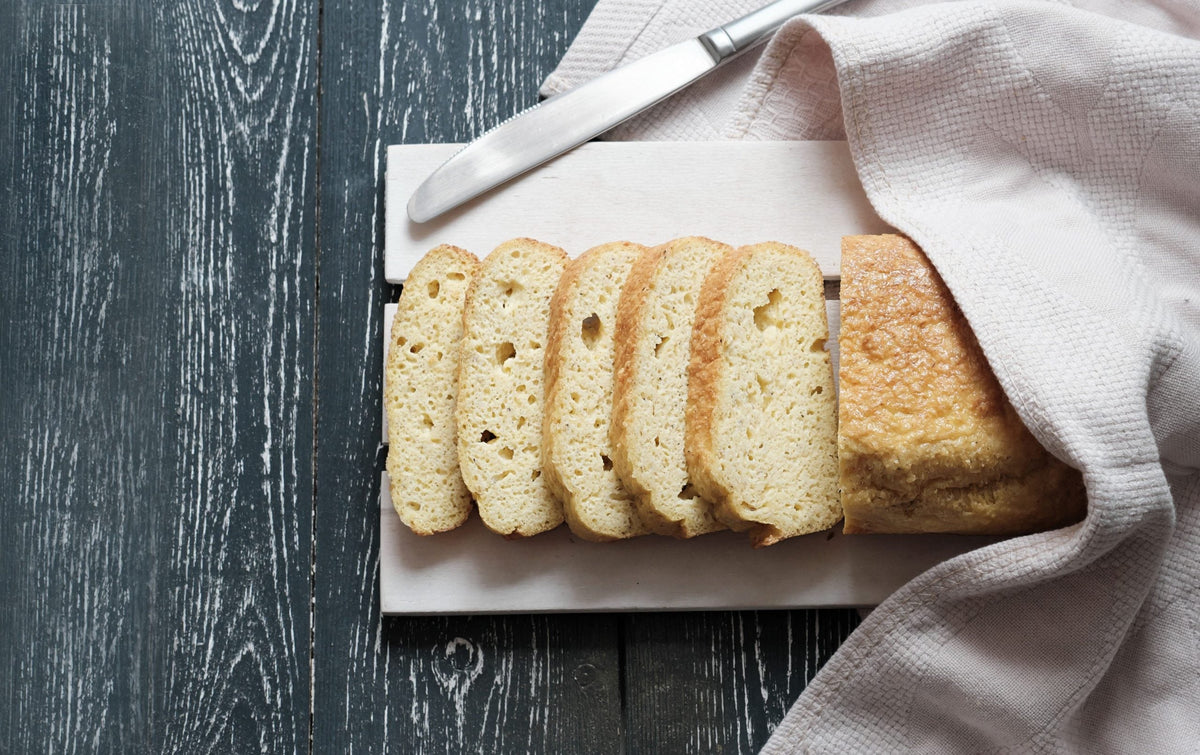 A sliced loaf of bread on a tray beneath a cloth.