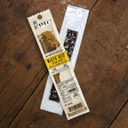 A Wagyu beef steak strip is displayed in a clear package on a wooden surface, featuring a label with a cow image, nutritional information, and the brand name "EPIC."
