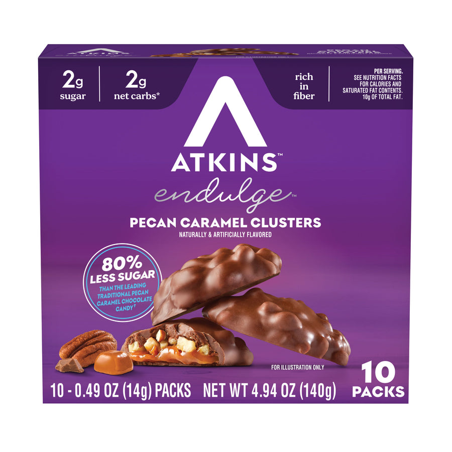 A purple box of Atkins Endulge Pecan Caramel Clusters displays the product name and nutritional information, with chocolate-covered clusters and pecans shown alongside the box.