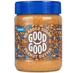 A jar of Good Good crunchy peanut butter with a blue lid displays labels indicating "no added sugar," "26g protein per 100g," and "8.5g fiber per 100g," set against a black background.