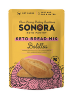 A yellow package of Sonora Keto Bread Mix features the product name prominently, with illustrations of bolillos and text highlighting low net carbs and preparation instructions.
