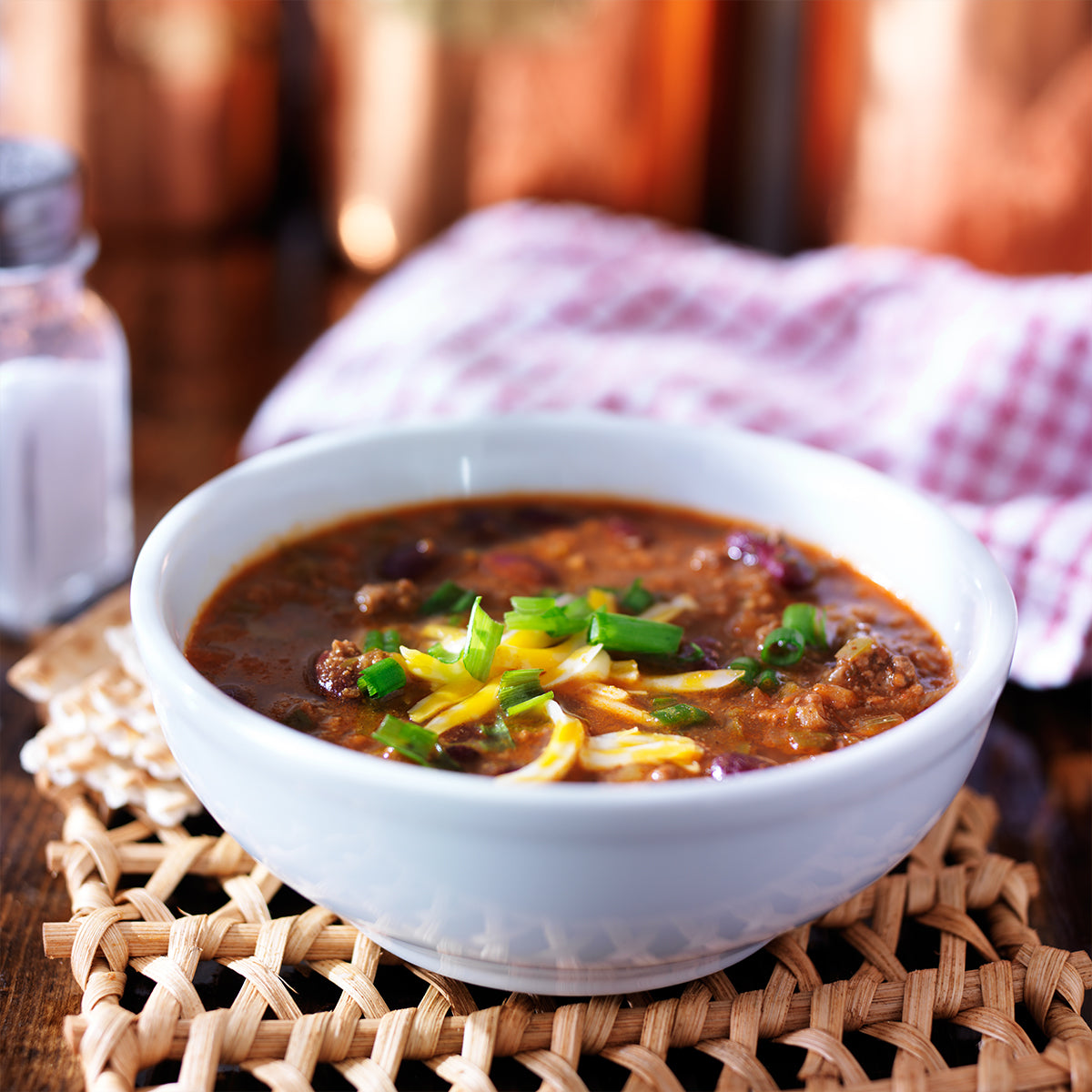 Bowl of prepared chili topped with scallions and cheese.