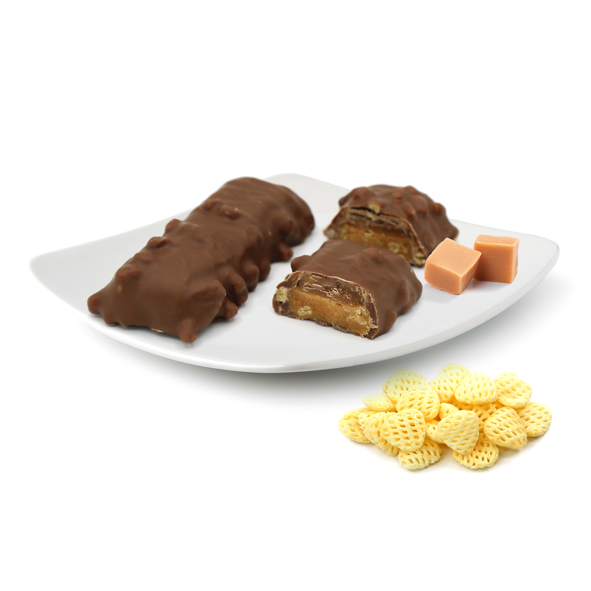 Chocolate-covered snack bars with a crunchy texture, revealing layers of caramel and nougat, accompanied by caramel squares and small yellow waffle-shaped snacks on a white plate.