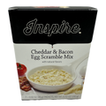 A box of Inspire Cheddar & Bacon Egg Scramble Mix features a bowl of the mix with a creamy texture, alongside a tomato and bacon, highlighting its natural flavors and serving suggestion.