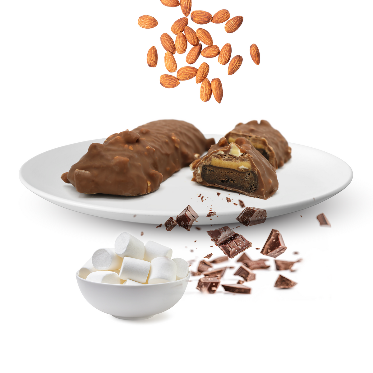A white plate holds two chocolate-covered protein bars, one cut in half to reveal layers of nuts and chocolate, surrounded by scattered almonds, chocolate pieces, and a bowl of marshmallows.
