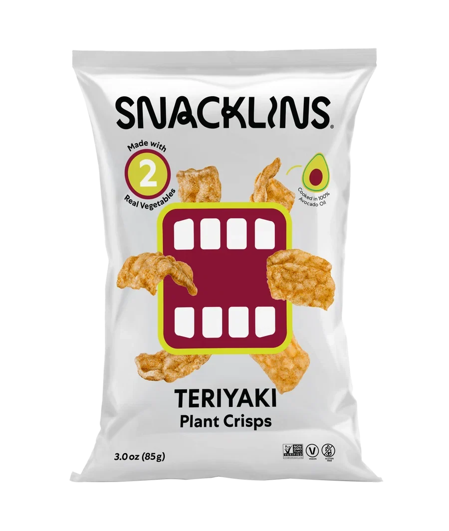 A bag of Snacklins Teriyaki Plant Crisps features a playful design with crispy snacks and highlights that it is made with real vegetables and cooked in avocado oil.