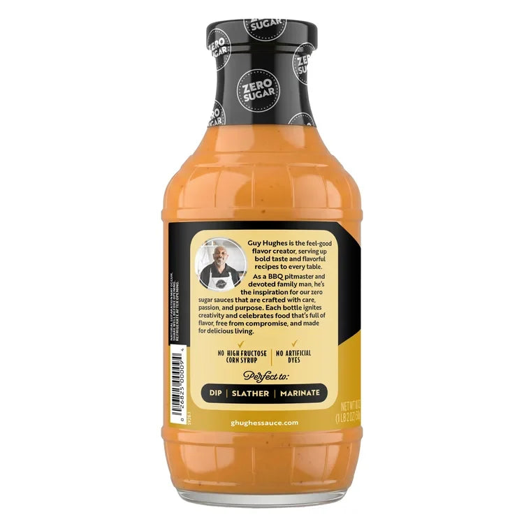 A bottle of zero sugar sauce features a black label with a photo of Guy Hughes, highlighting his role as a BBQ expert and the sauce's uses for dipping, slathering, and marinating.