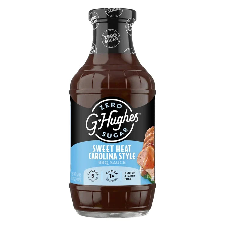 A clear bottle of G. Hughes Sweet Heat Carolina Style BBQ sauce displays a black and blue label, highlighting its zero sugar content and gluten-free features.