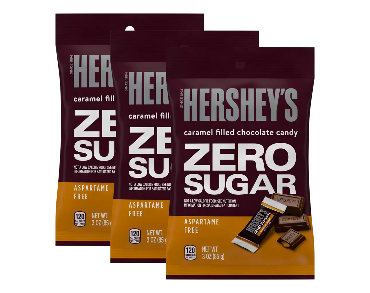 Three bags of Hershey's Zero Sugar caramel-filled chocolate candy are displayed, featuring bold text highlighting "ZERO SUGAR" and "ASPARTAME FREE," with each bag containing 3 ounces.