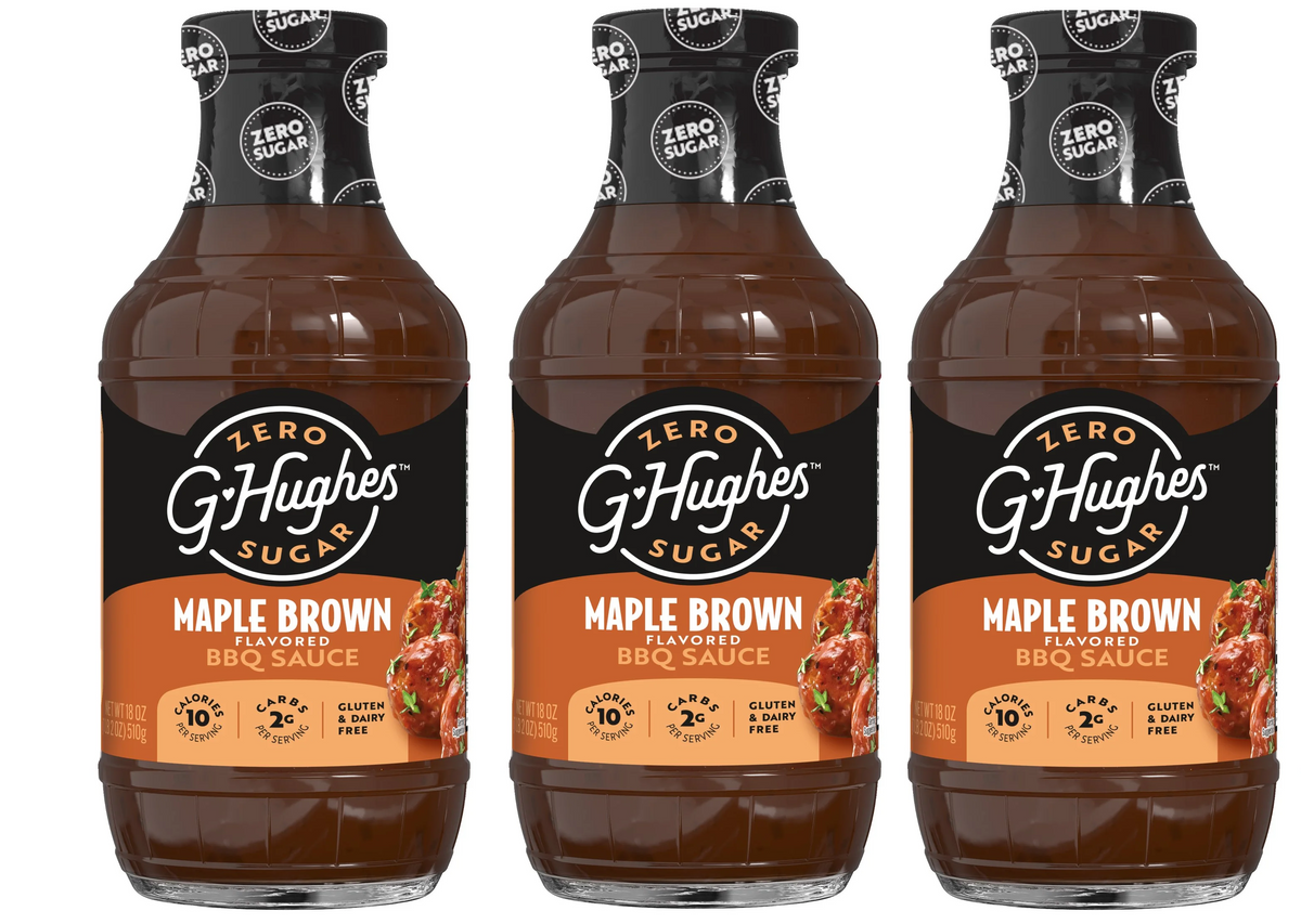 Three bottles of G Hughes Zero Sugar Maple Brown Flavored BBQ Sauce are displayed, featuring a dark brown liquid and labels highlighting "gluten & dairy free" and nutritional information.