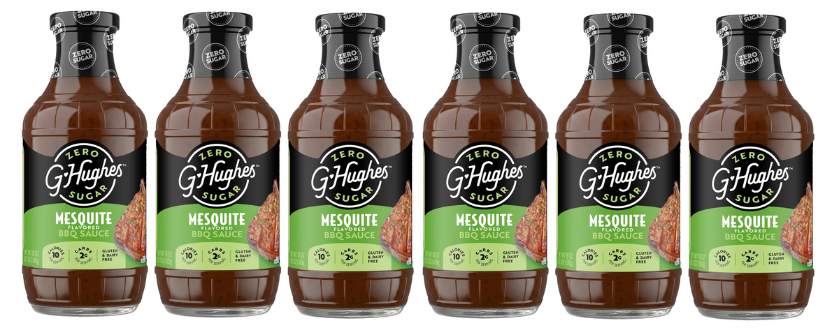 Six bottles of G. Hughes Zero Sugar Mesquite Flavored BBQ Sauce are lined up, each featuring a black label with green accents and a picture of grilled meat, highlighting its gluten and dairy-free attributes.