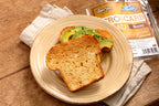 Toasted bread with avocado on a plate beside a package of ThinSlim Foods Honey Bread.