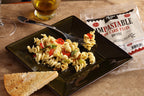 Cooked rotini with vegetables and a slice of bread beside an Impastable Rotini package.