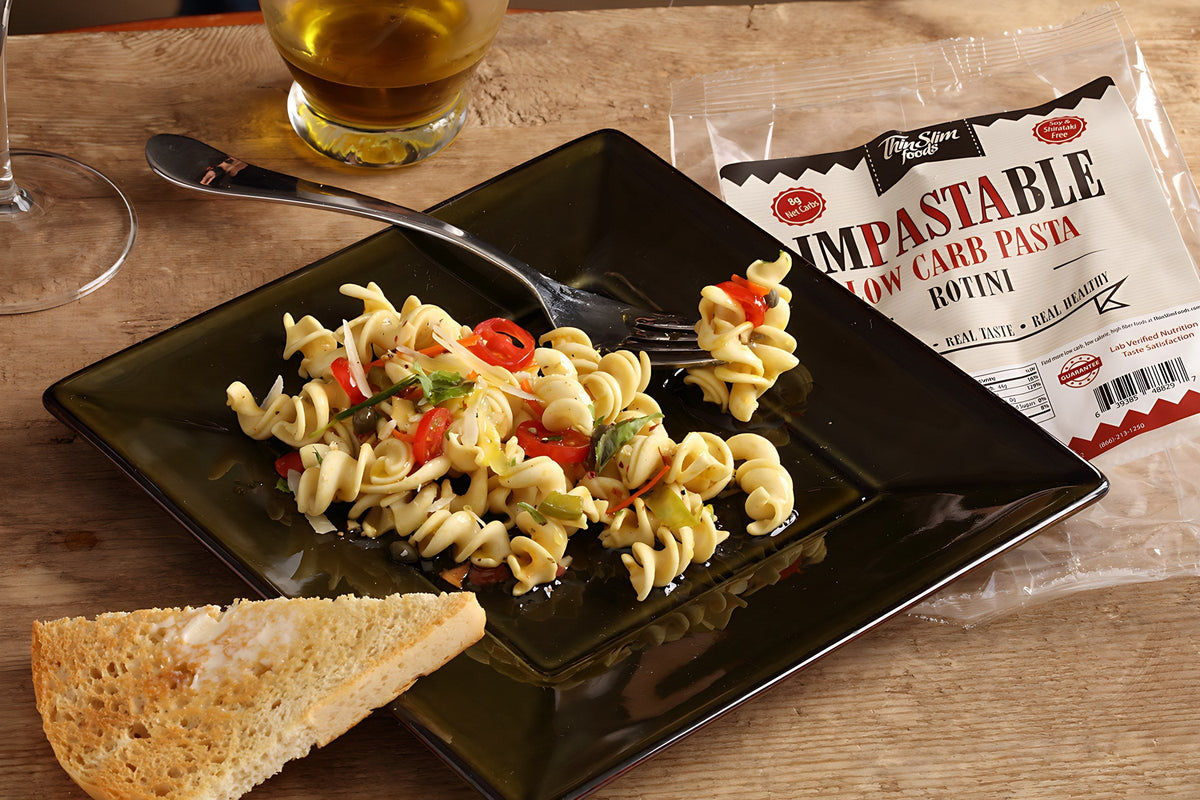 Cooked rotini with vegetables and a slice of bread beside an Impastable Rotini package.