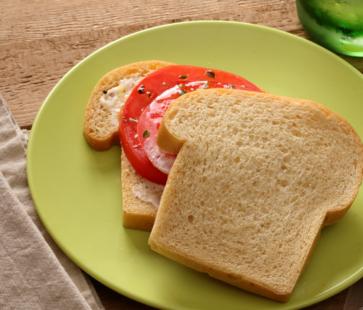 Tomato sandwich made with plain sliced bread on a green plate