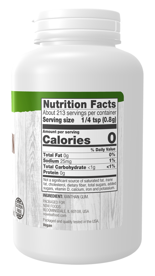A white plastic container of xanthan gum displays nutrition facts, including serving size, calories, and ingredient details, with a wooden texture background and a gluten-free label.