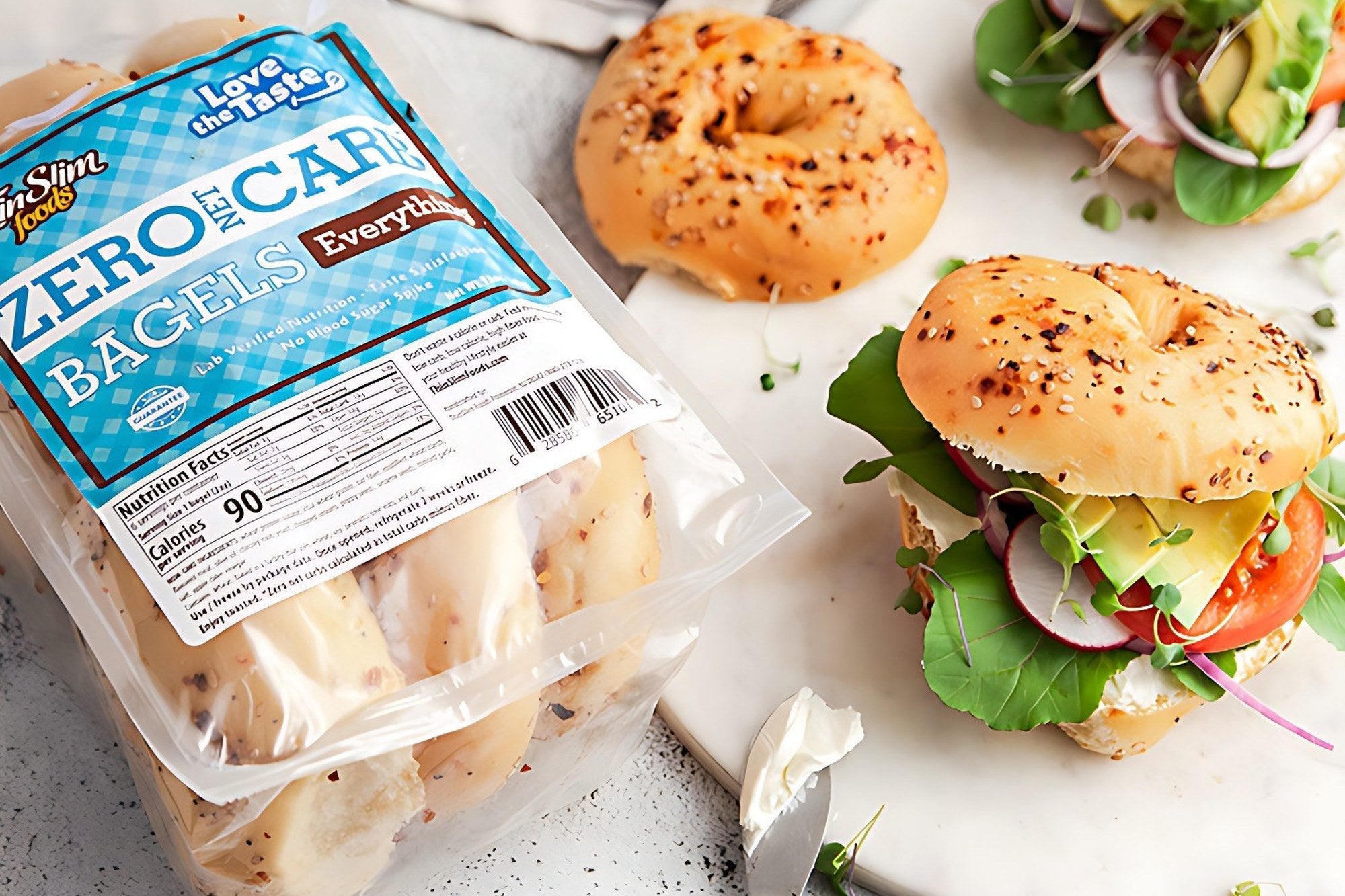 ThinSlim Foods Everything Bagels in a clear pouch beside a bagel and a vegetable bagel sandwich.